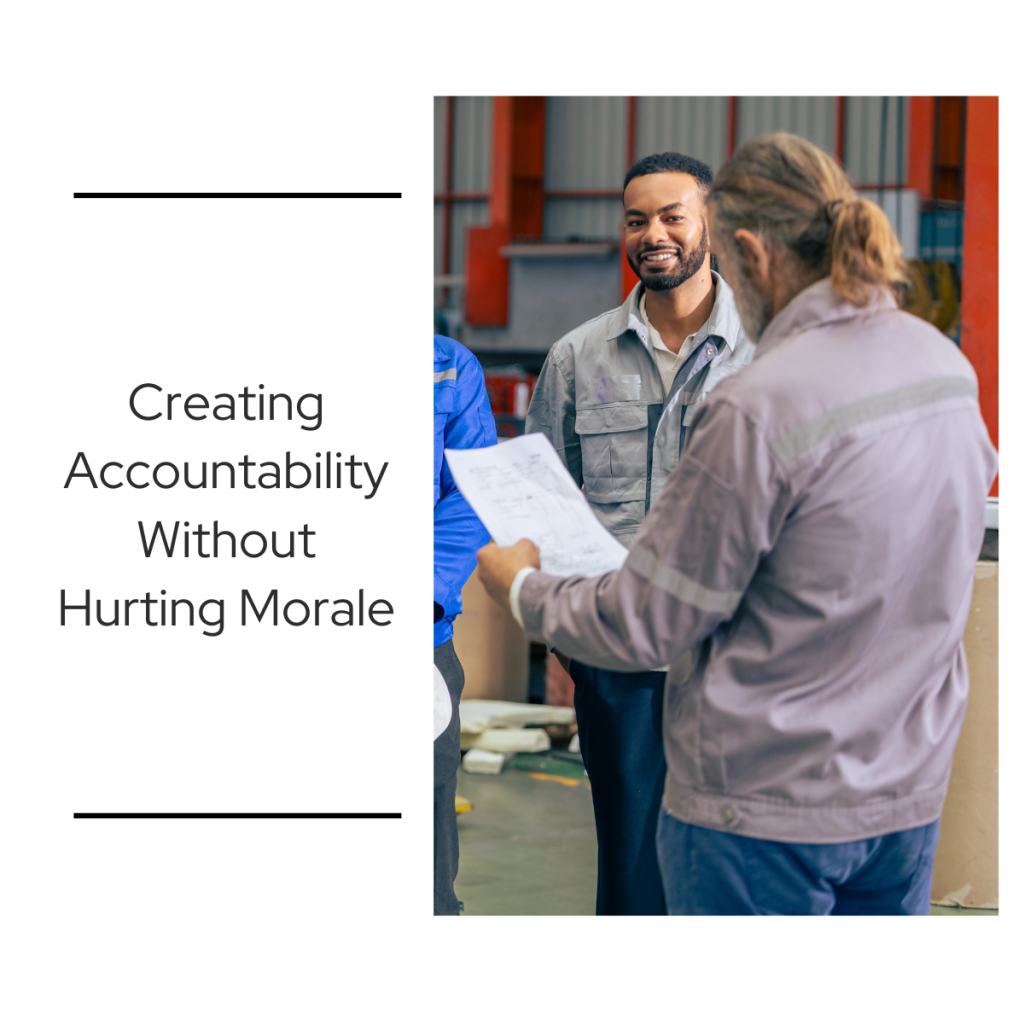 Supervisor reviewing paperwork with manufacturing employees on a production floor, representing accountability and maintaining morale in the workplace.